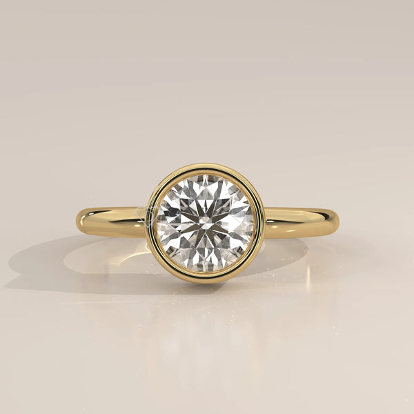 A classic 14k yellow gold ring with a bezel-set round diamond.