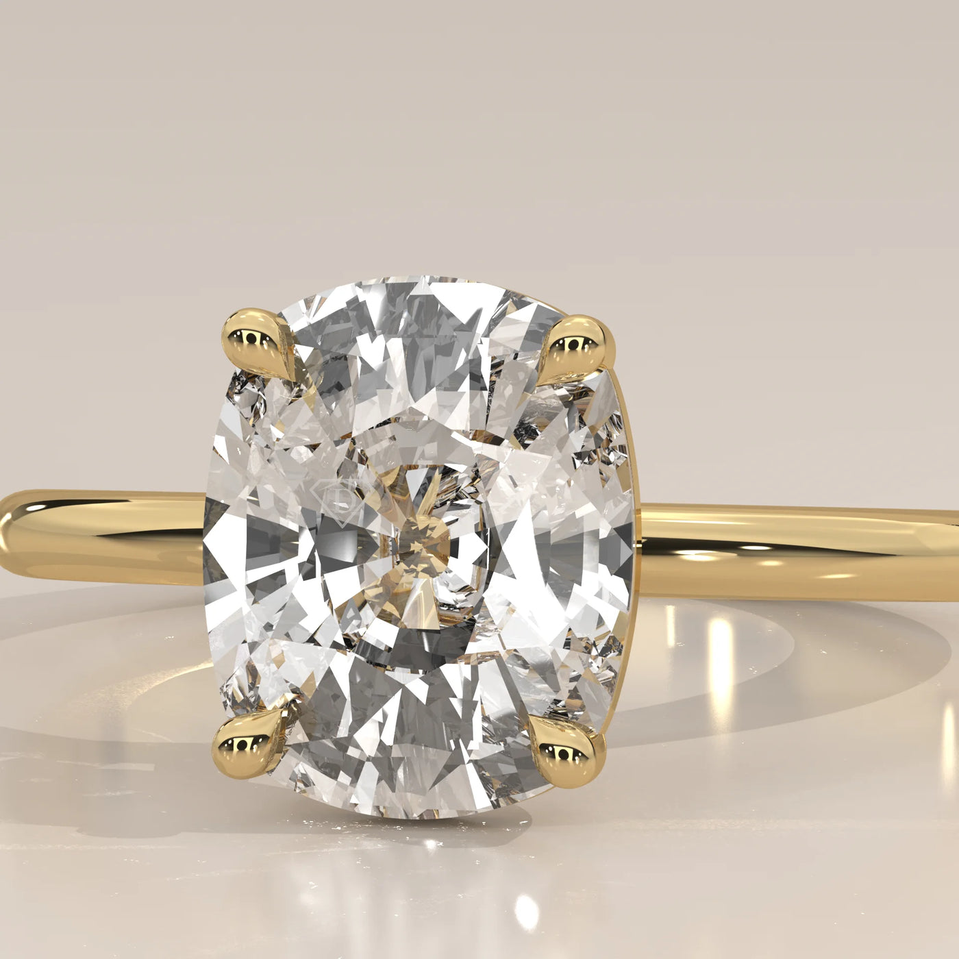 A close-up studio shot of a 14k yellow gold ring with a cushion-cut diamond.