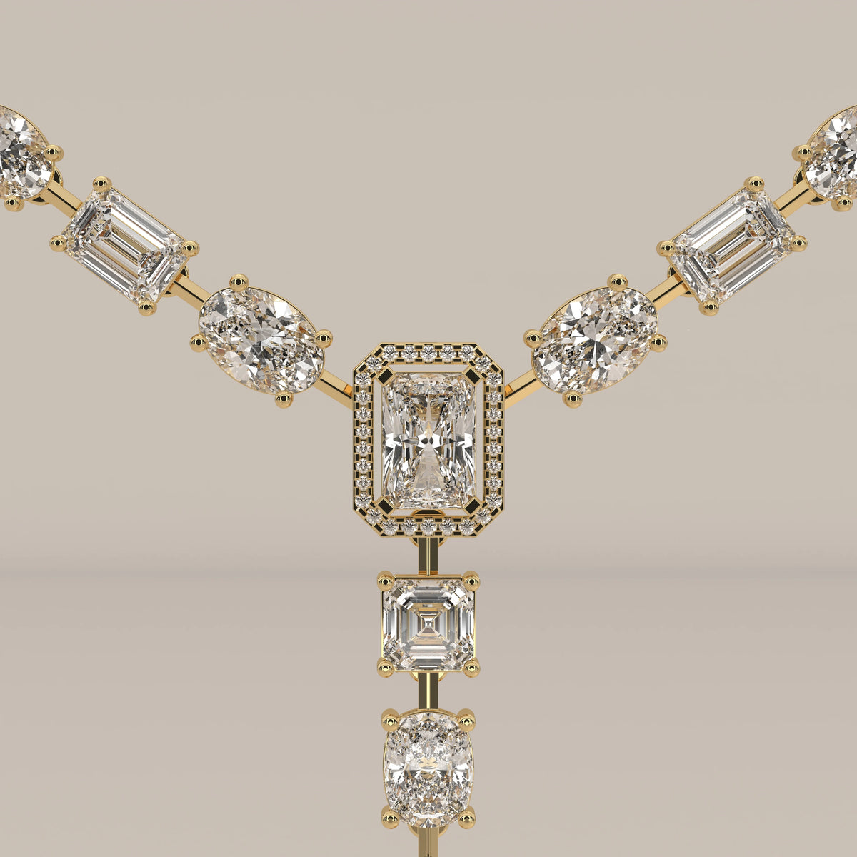An emerald cut halo y-drop lab grown diamond necklace in yellow gold, photographed head-on.