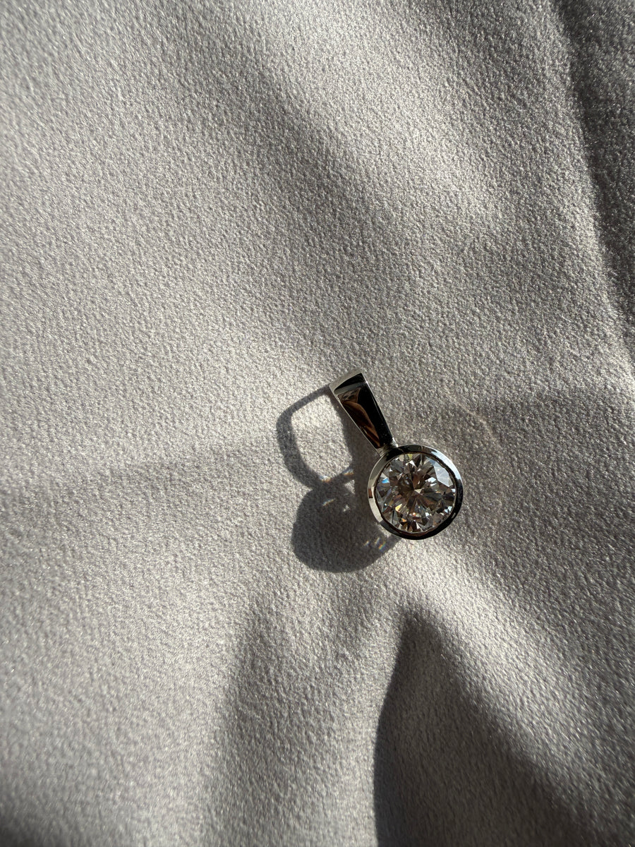 Bezel set round lab grown diamond solitaire pendant photographed in natural light