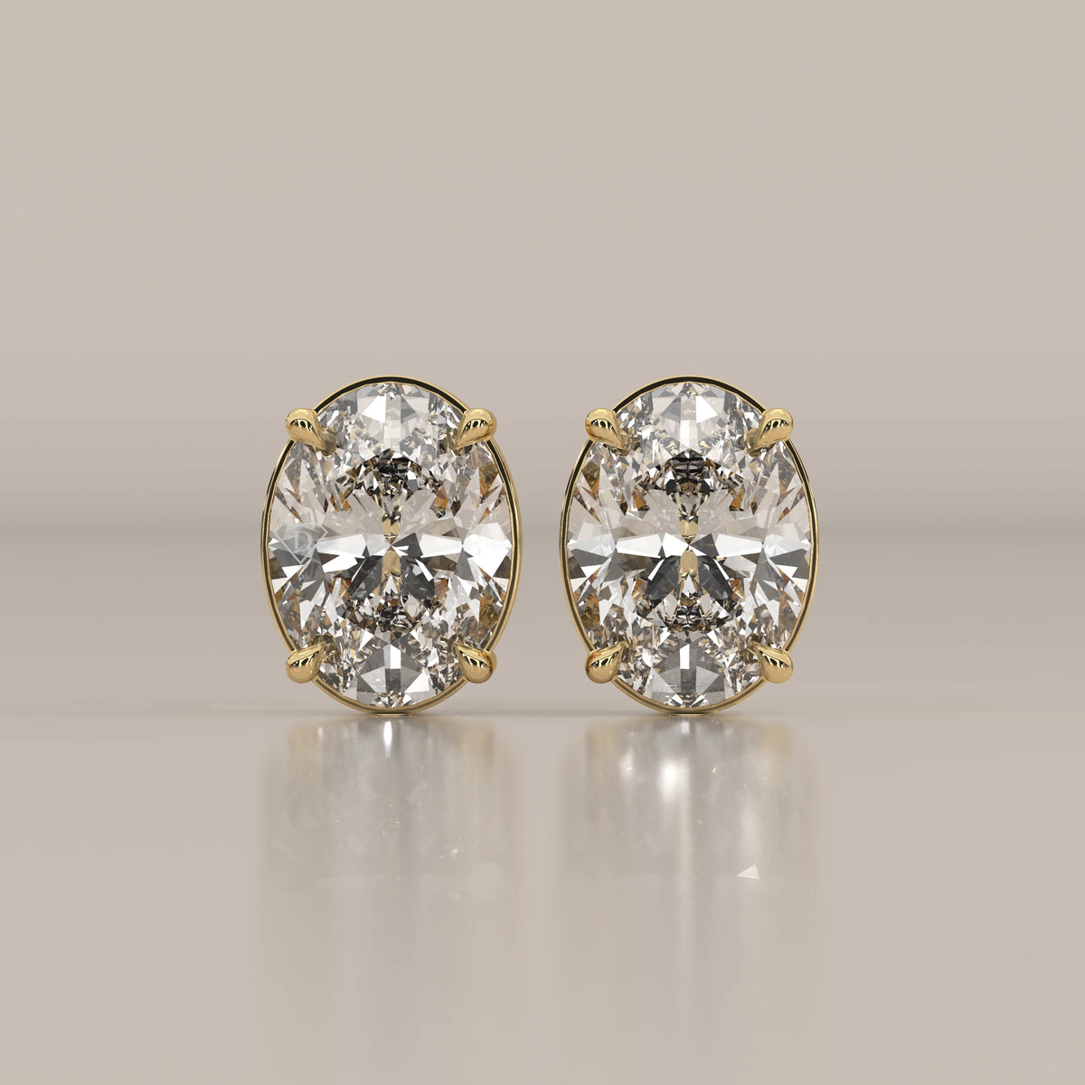 A pair of oval cut diamond stud earrings set in yellow gold.