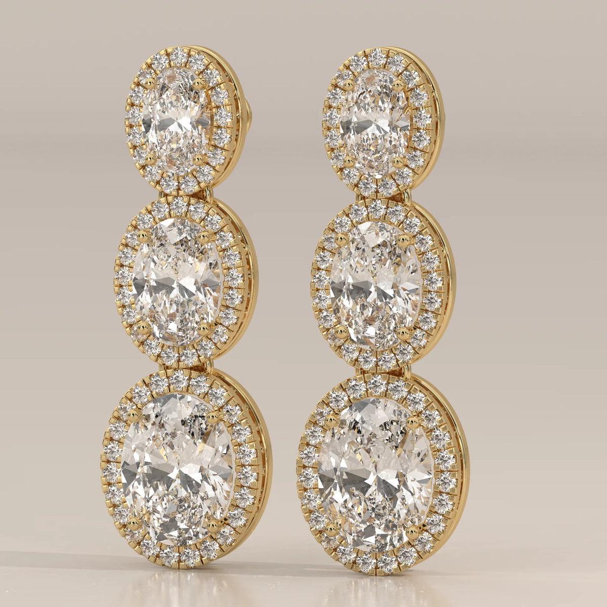 Graduated Three Oval Halo Lab Grown Diamond Drop Earrings in yellow gold, front view on a plain background.
