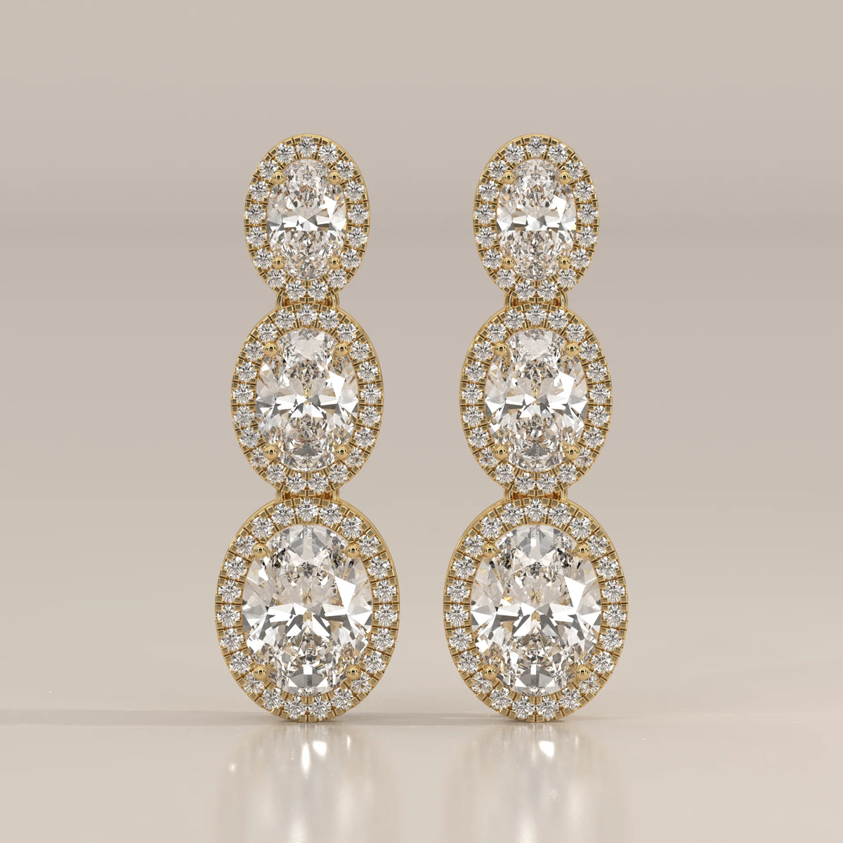 Graduated Three Oval Halo Lab Grown Diamond Drop Earrings in yellow gold, shown from the front.