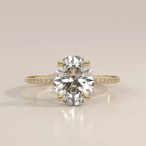 Oval cut diamond engagement ring with a paved band in yellow gold.