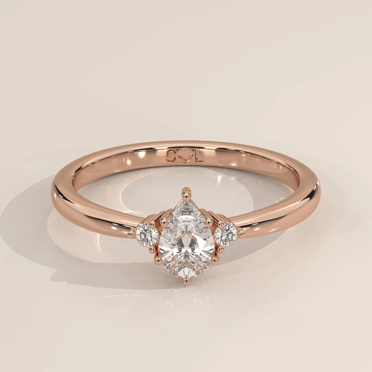 Pear lab grown diamond three stone engagement ring in 14k rose gold, three-quarter view