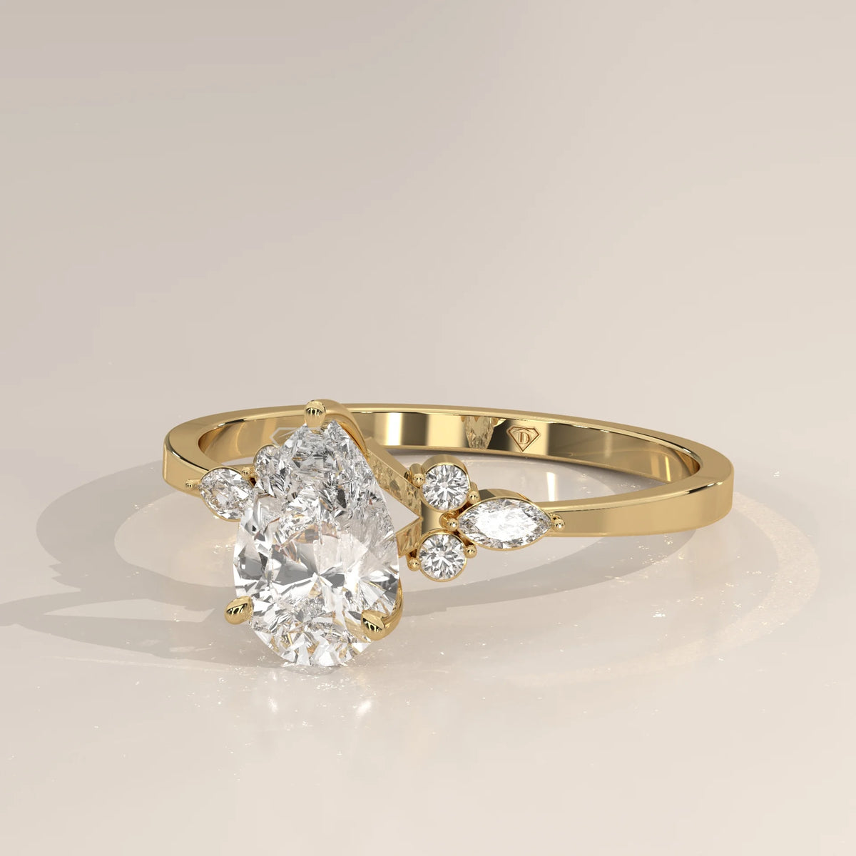 A delicate yellow gold ring with a pear-shaped diamond and smaller accent stones.