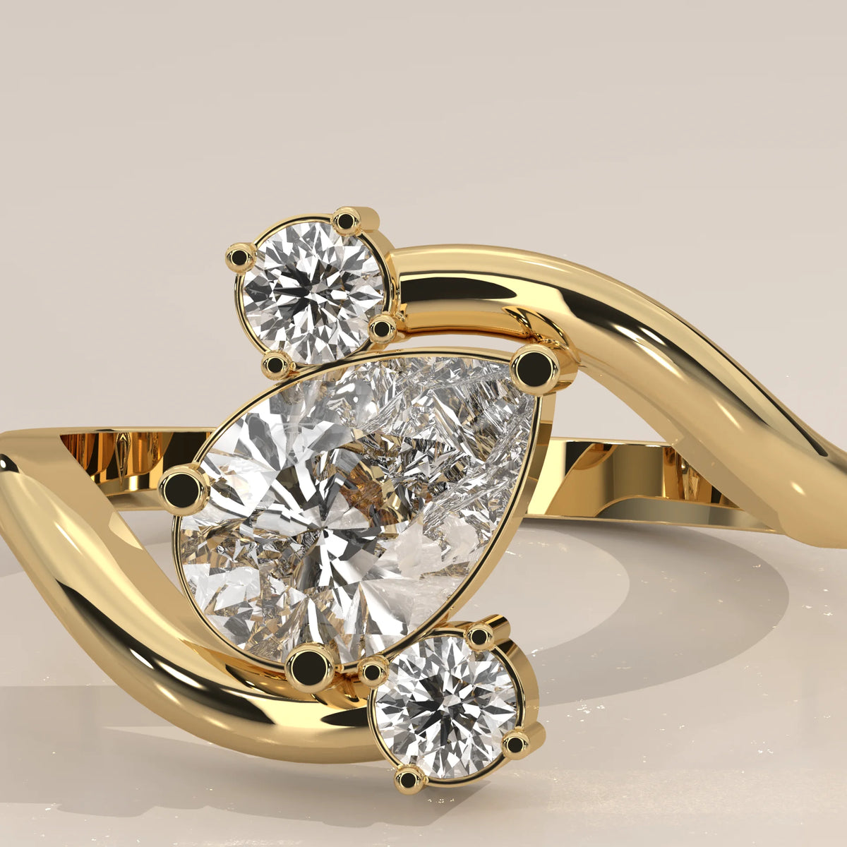 Yellow gold bypass ring with a pear-shaped diamond and two round accent diamonds.