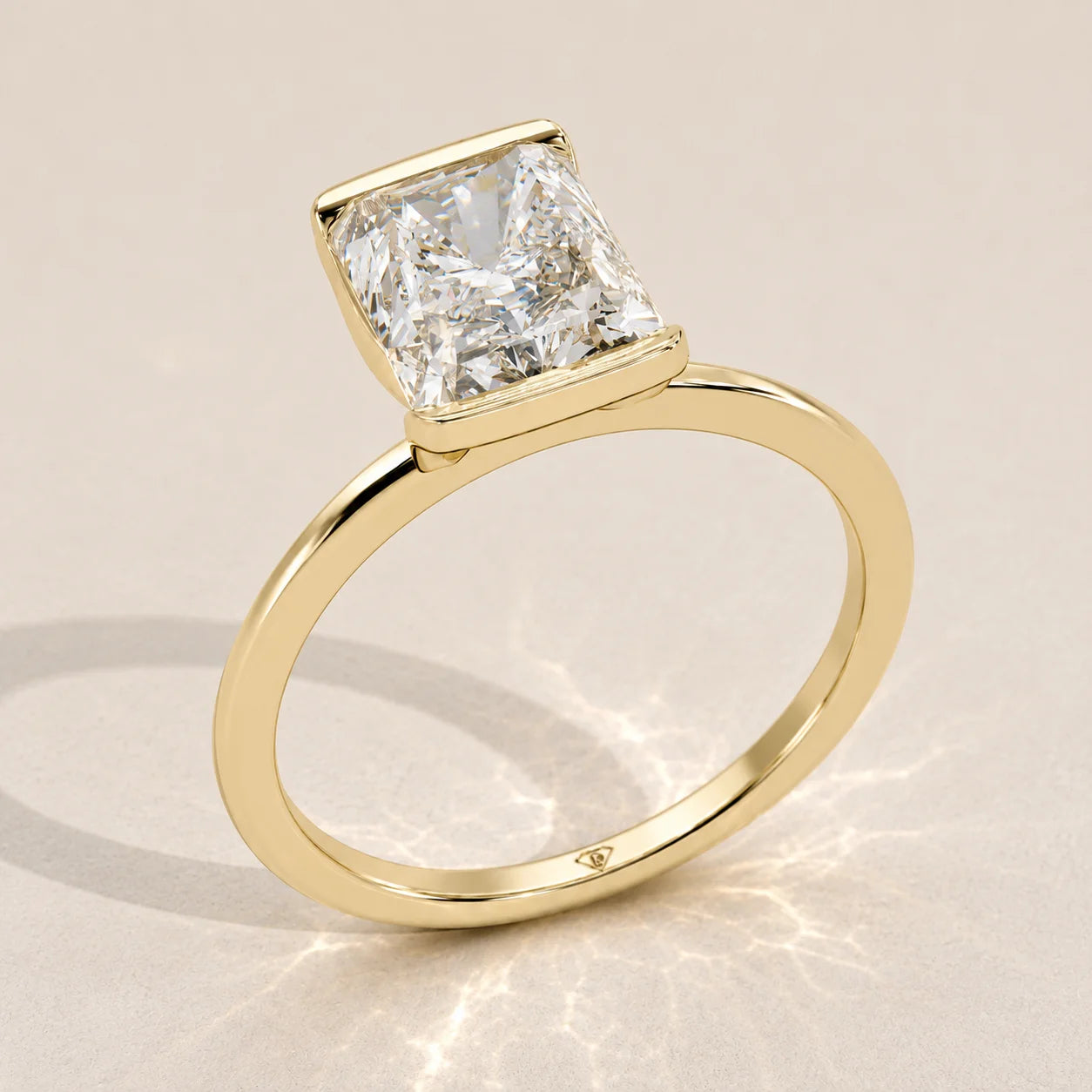 A 14k yellow gold ring with a radiant cut diamond in a bezel setting.
