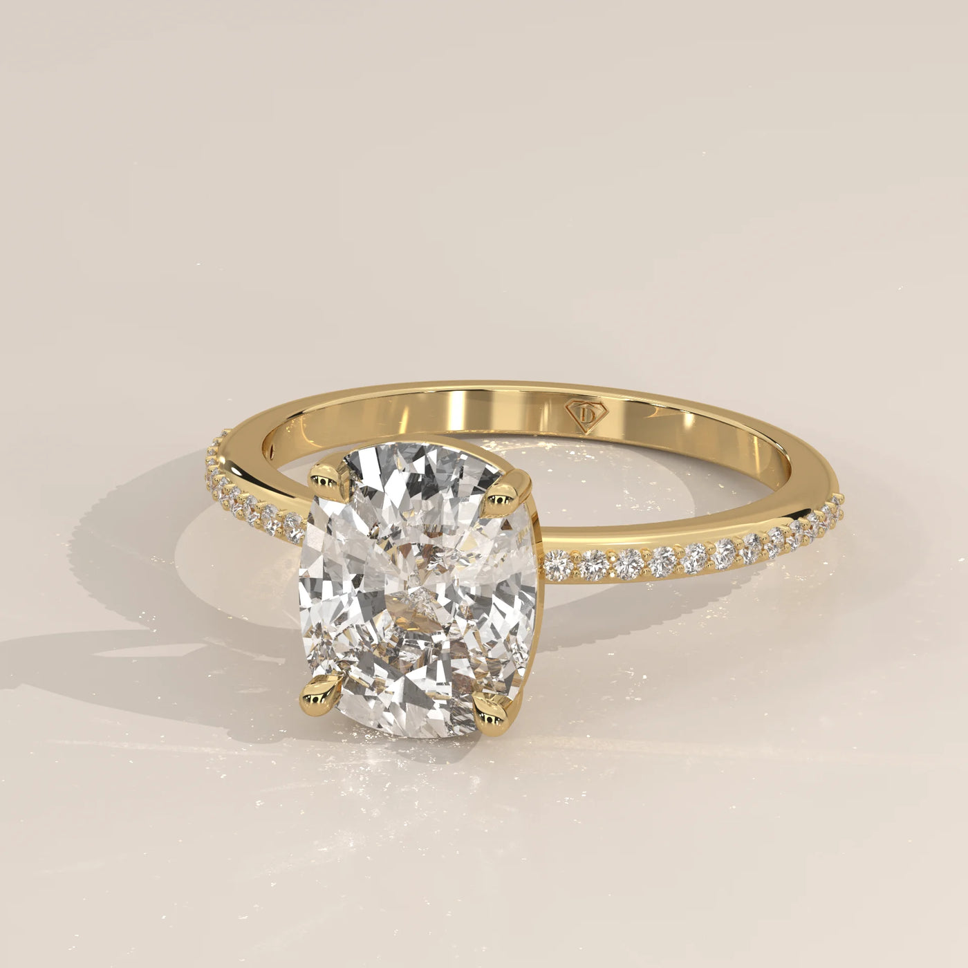 A cushion-cut diamond ring with pavé band in yellow gold.