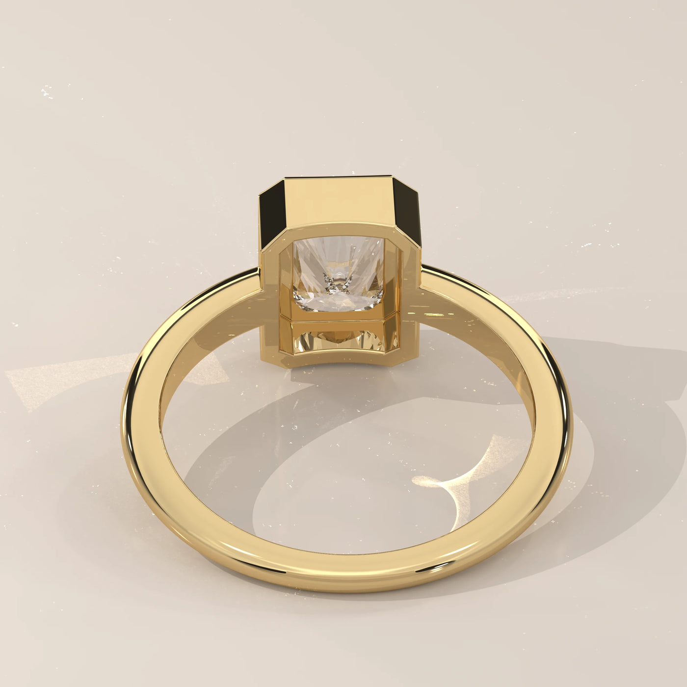 A yellow gold ring featuring a bezel-set emerald-cut diamond.