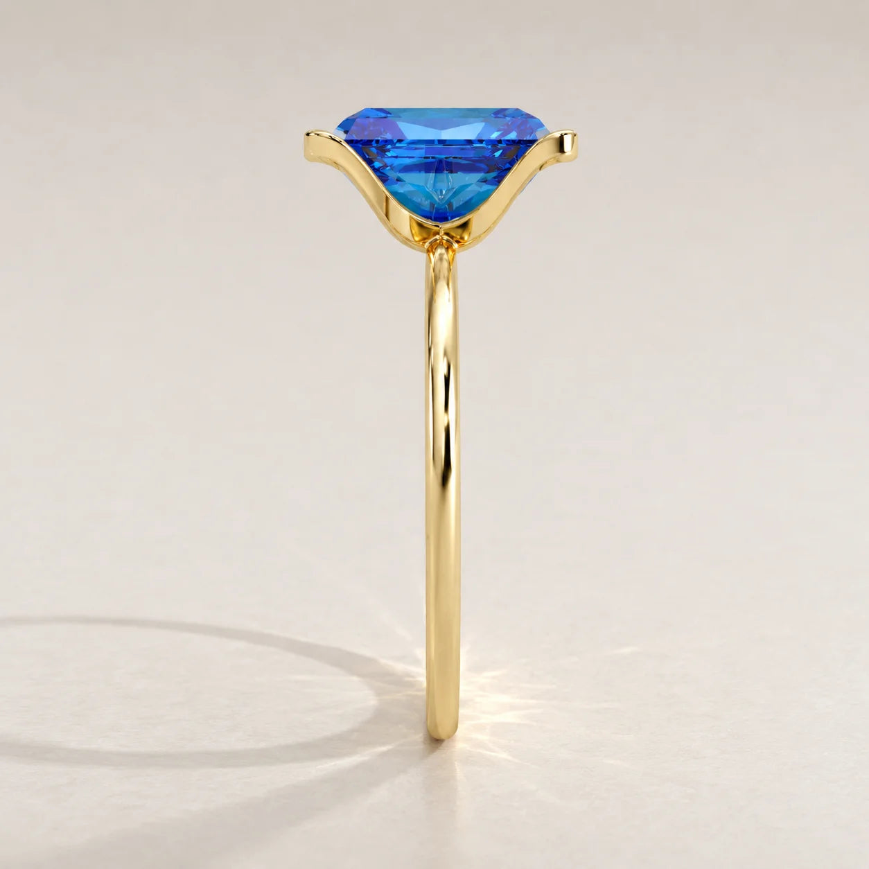 A simple gold ring holding a bright blue gemstone, shown from the side.