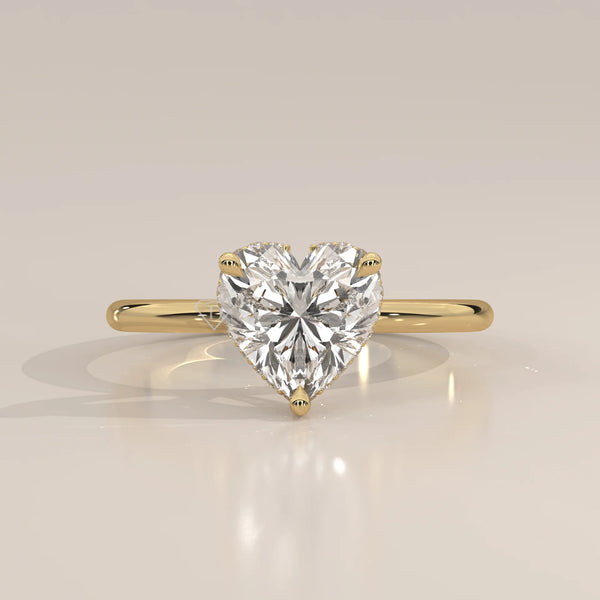 A yellow gold ring with a heart-shaped diamond in a bezel setting.