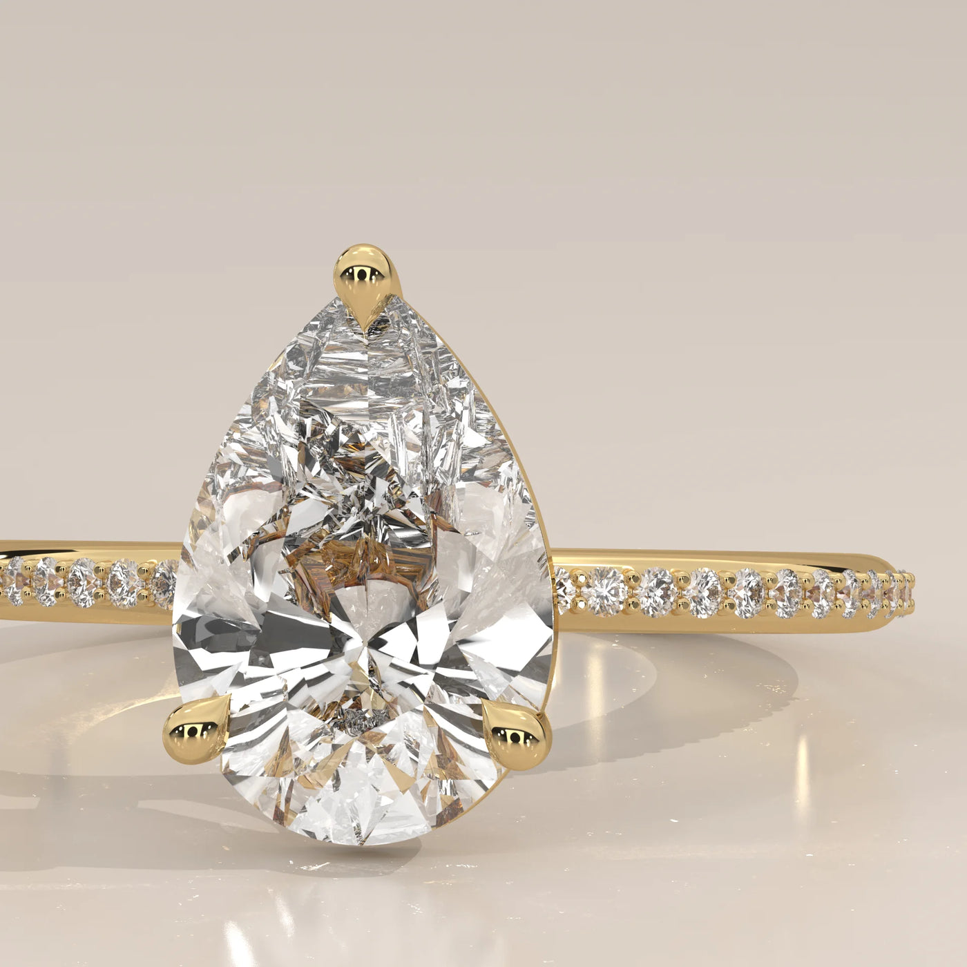 A close-up of a pear-shaped diamond engagement ring with small diamonds on the band.