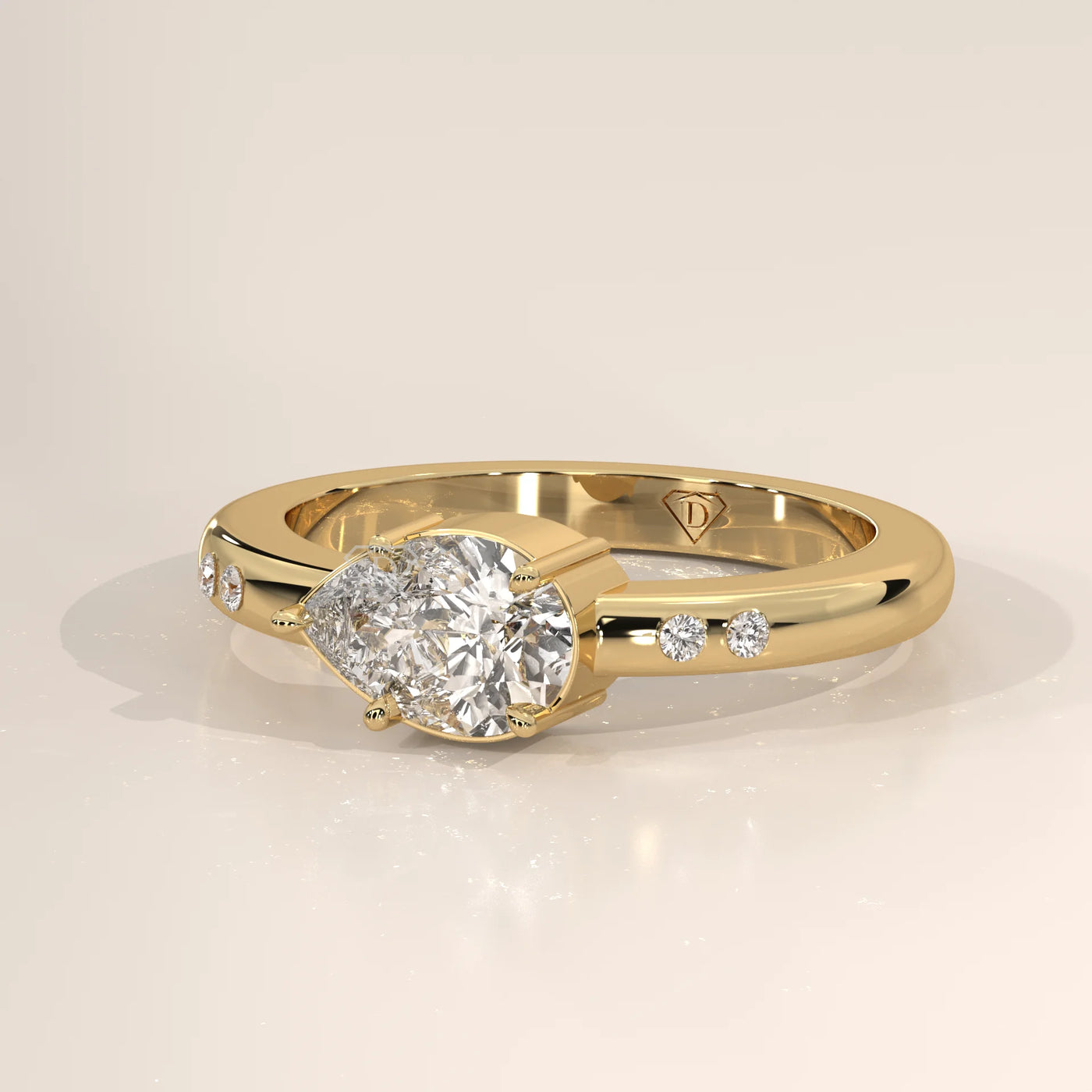 A delicate 14k gold ring with a pear-shaped diamond, shown from the side.