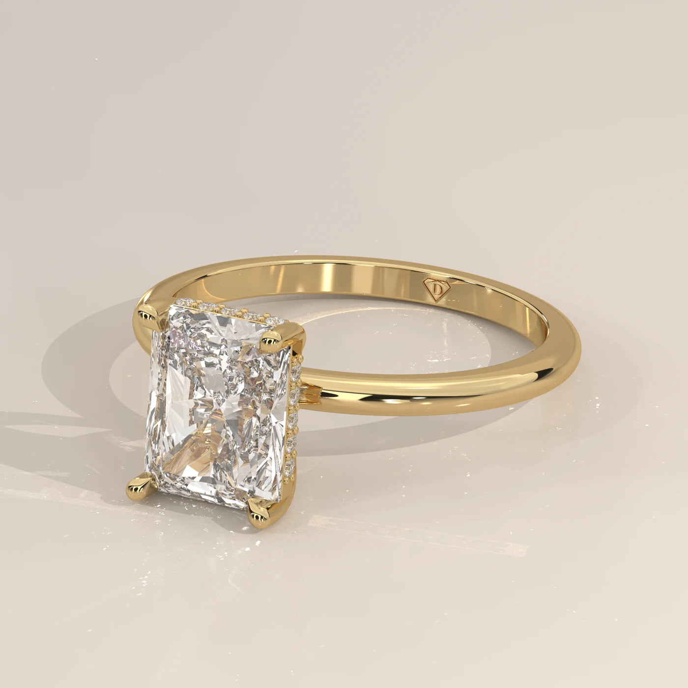 A radiant cut diamond set in a 14k yellow gold band with small diamonds along the setting.