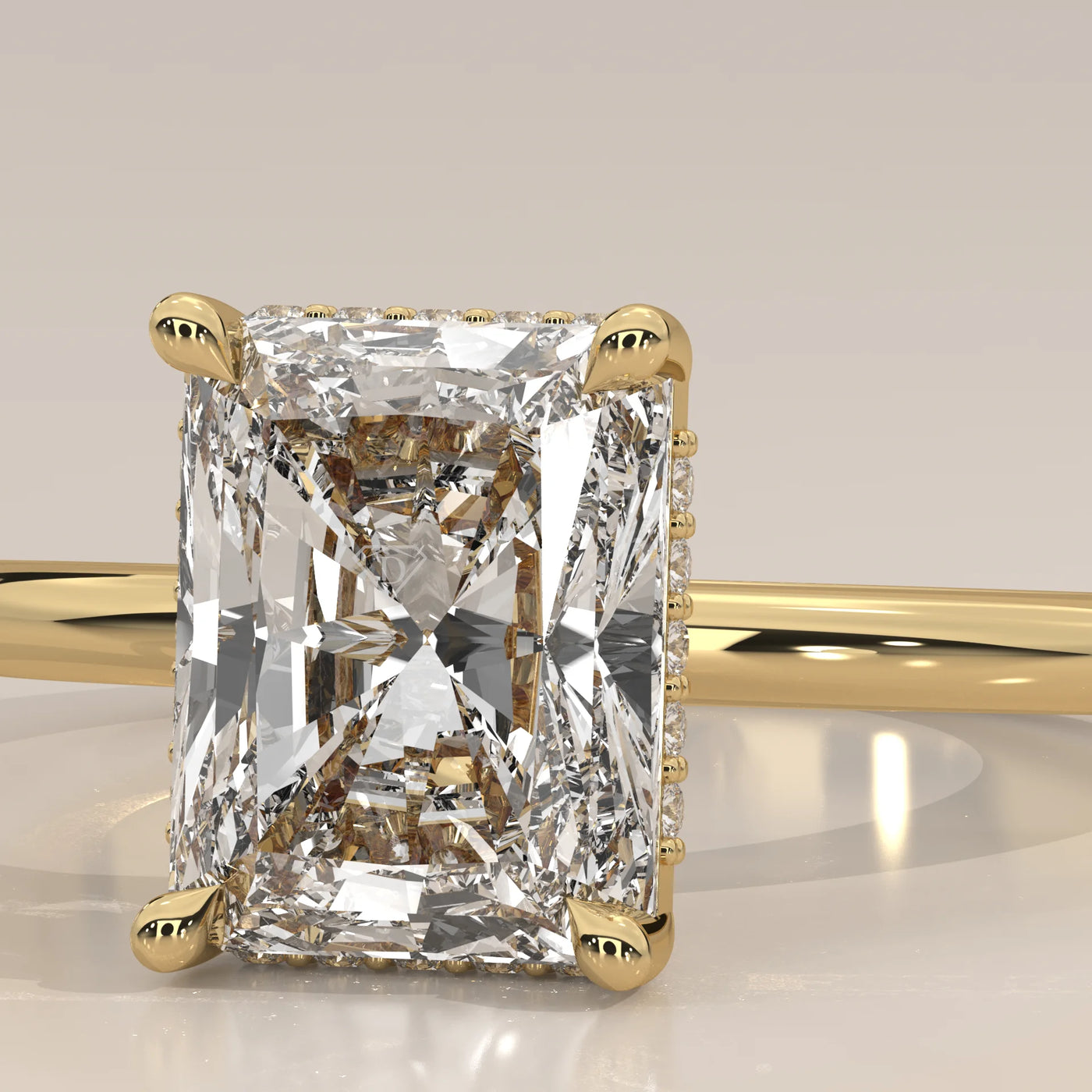 A close-up of a radiant cut diamond engagement ring in yellow gold.