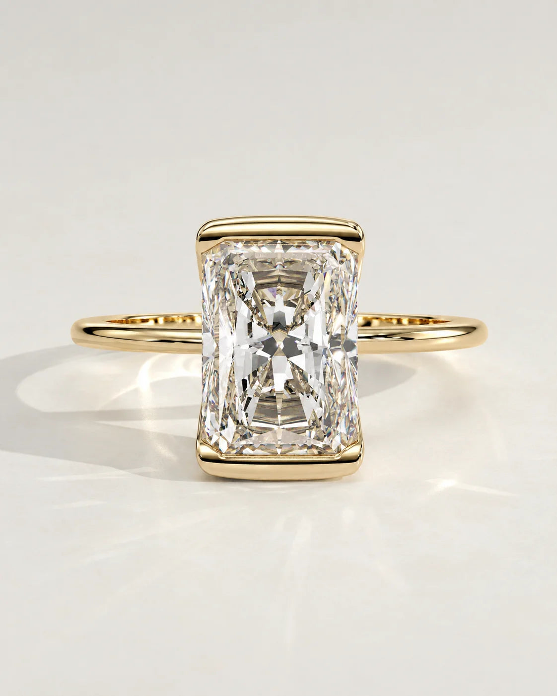 A radiant cut diamond engagement ring set in a yellow gold bezel.