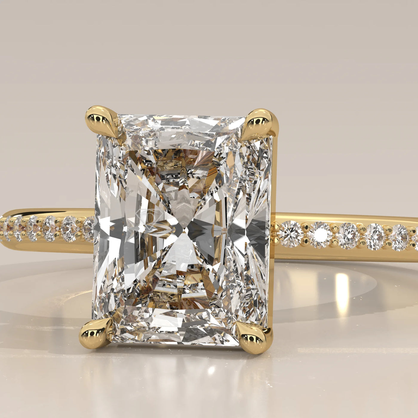 Radiant cut diamond ring with pave band in yellow gold.