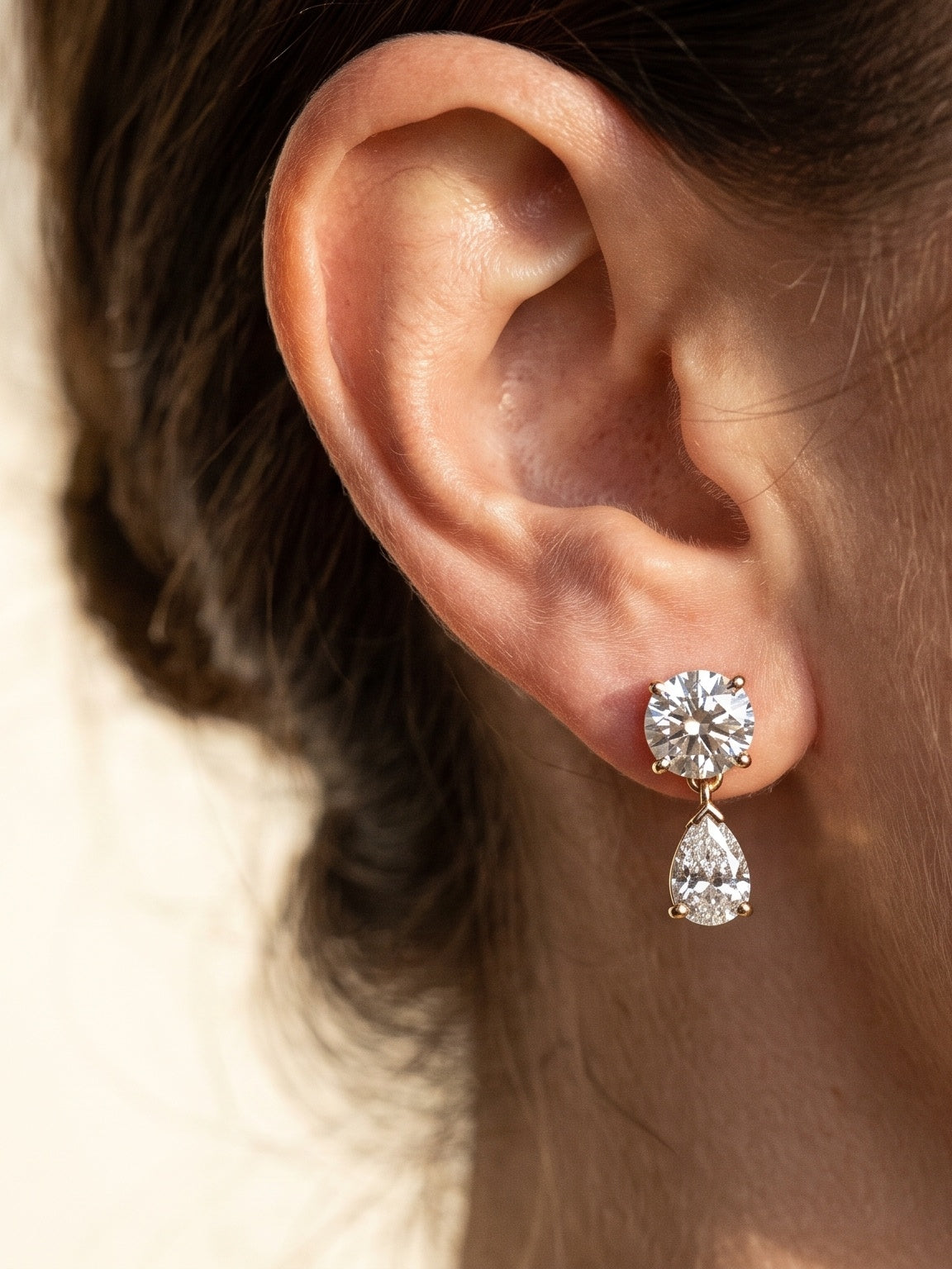 Close-up of diamond drop earring worn on model's ear