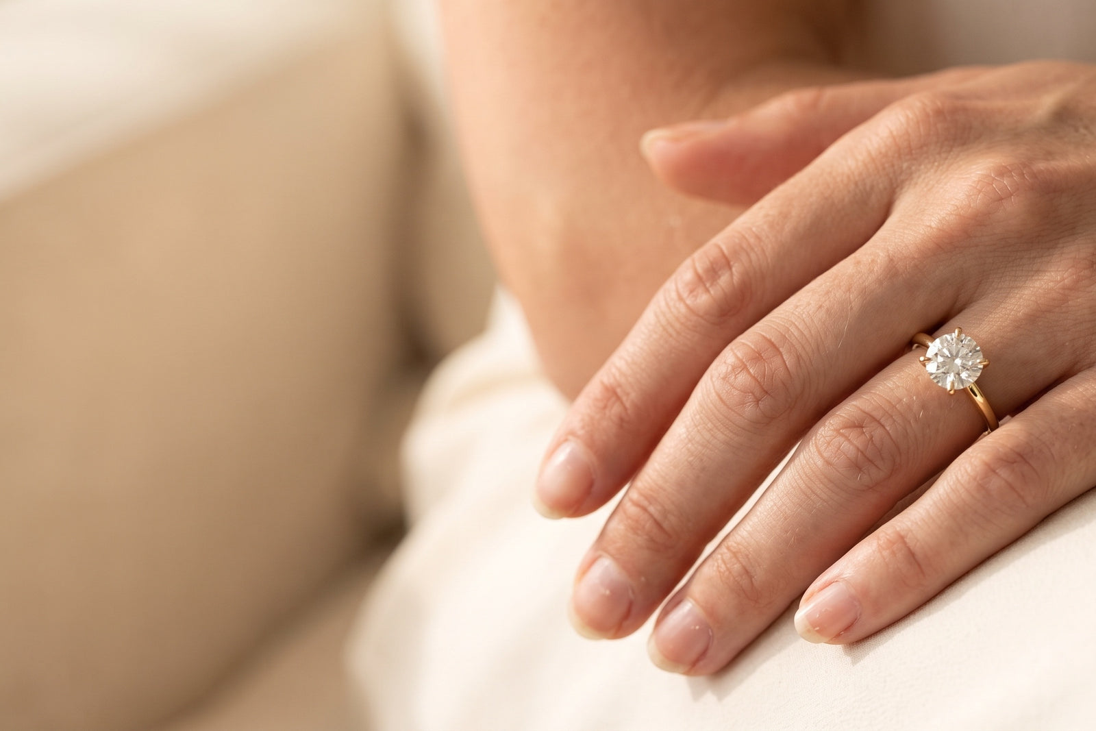 Woman's hand wearing a round solitaire diamond engagement ring