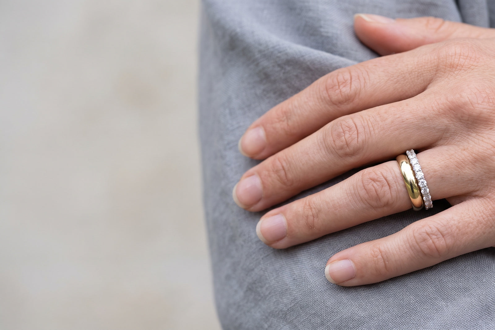 Woman's hand wearing a stacked gold and diamond wedding band set