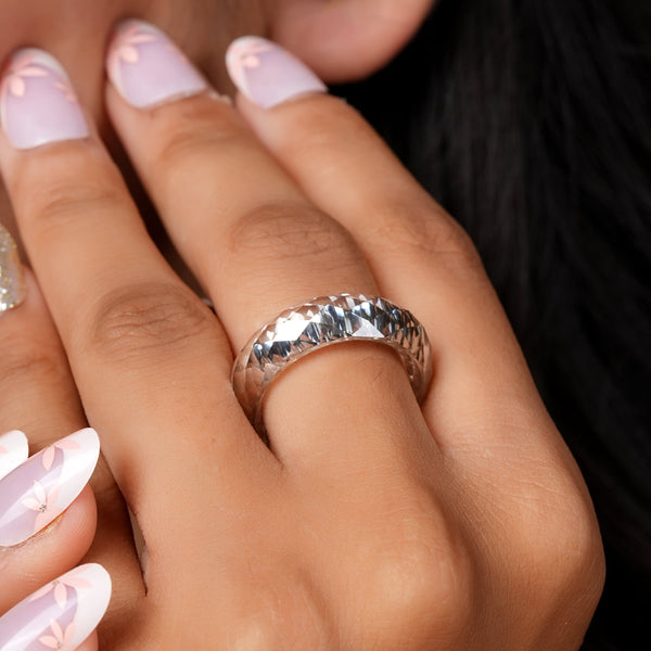 Close-up of a hand with a silver ring and pink nail polish.