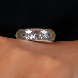 Silver ring with a large diamond on a finger against a black background
