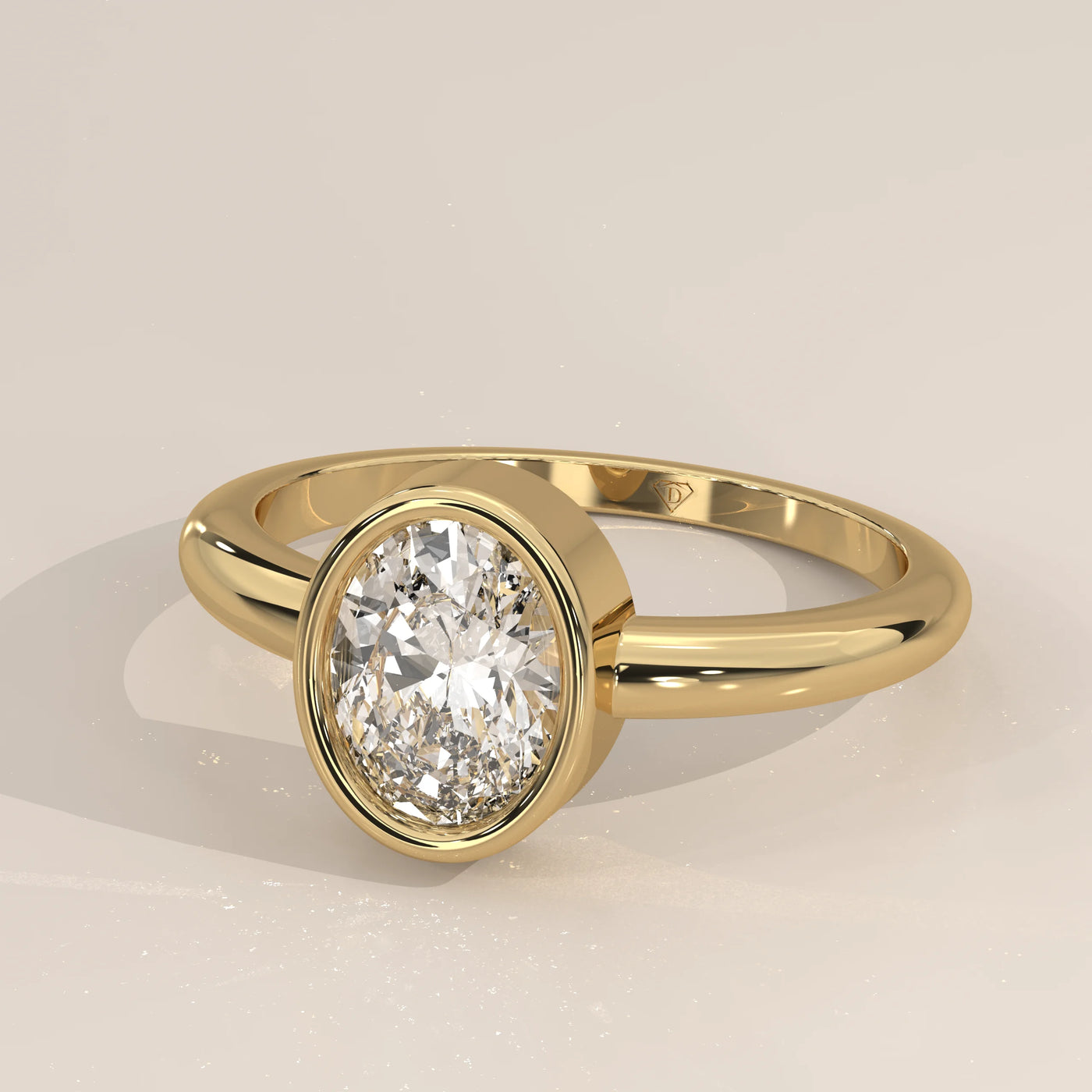 Oval diamond engagement ring with a yellow gold bezel setting.