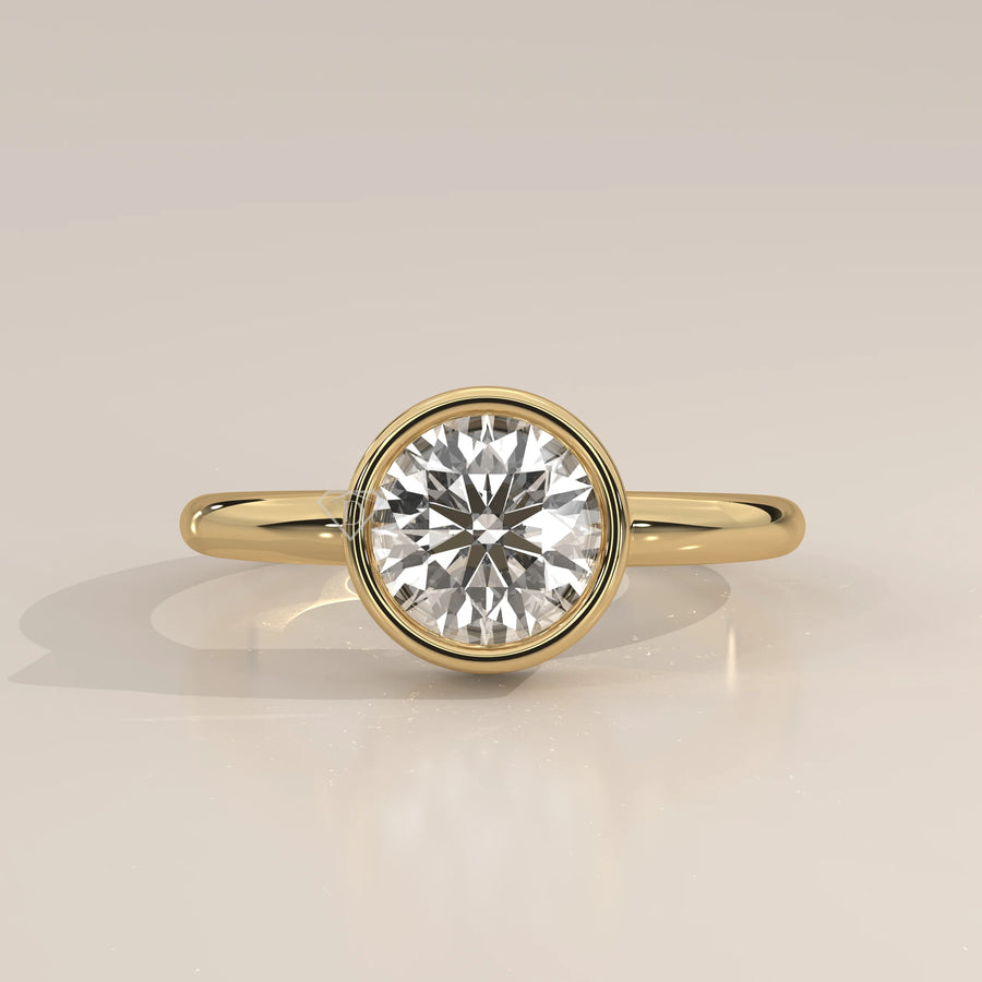 A classic 14k yellow gold ring with a bezel-set round diamond.