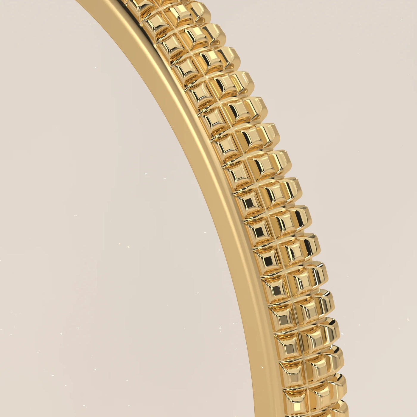 Close-up view of a textured gold bangle bracelet on a light background.