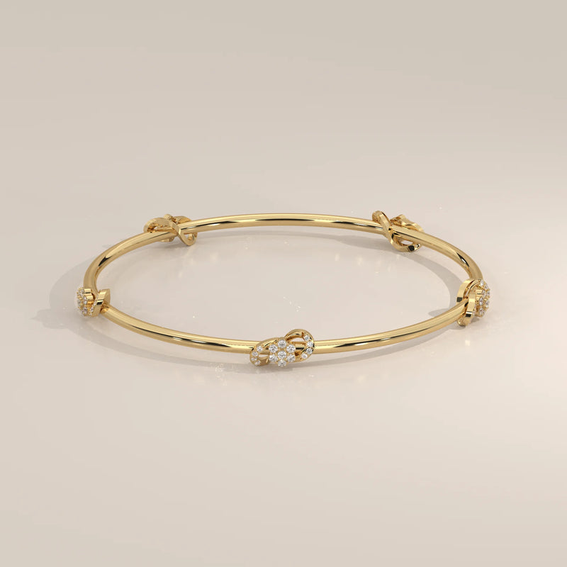 A delicate gold bangle bracelet adorned with diamond-encrusted knots.