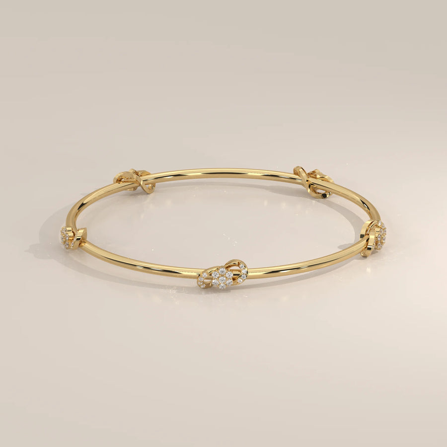 A delicate gold bangle bracelet adorned with diamond-encrusted knots.
