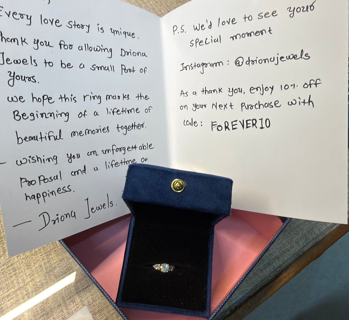 Handwritten Driona Jewels note beside a lab grown diamond engagement ring in a navy ring box