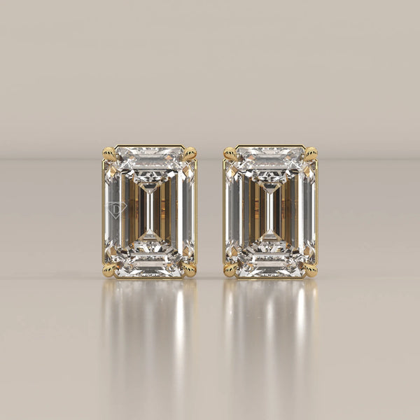 Pair of emerald cut diamond stud earrings in yellow gold.