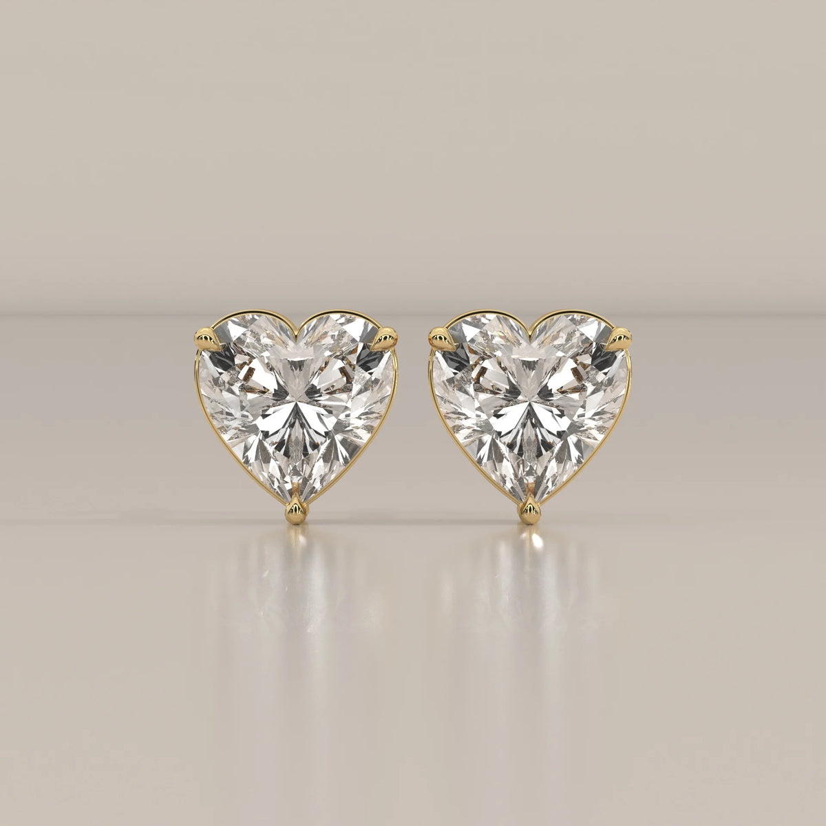 Pair of heart-shaped diamond stud earrings in 14k yellow gold.