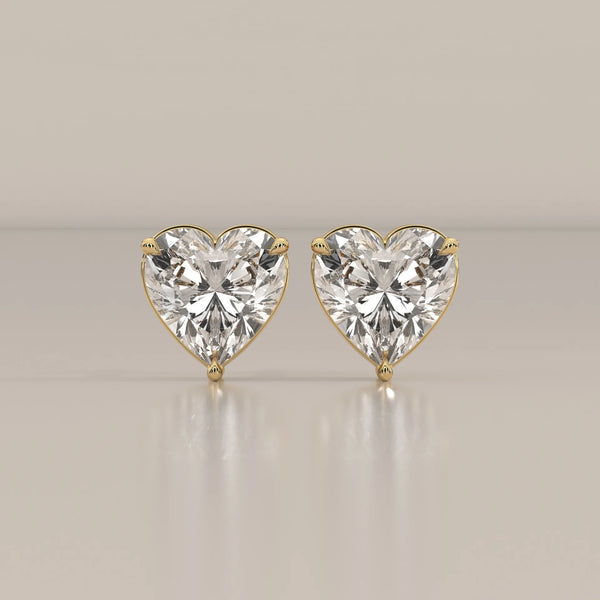 Pair of heart-shaped diamond stud earrings in 14k yellow gold.