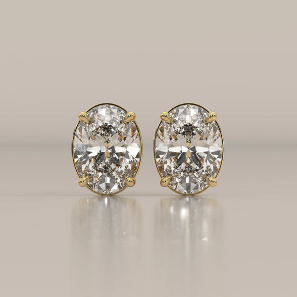 A pair of oval cut diamond stud earrings set in yellow gold.