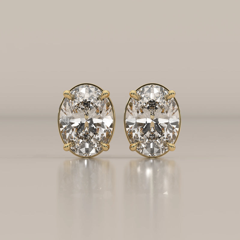 A pair of oval cut diamond stud earrings set in yellow gold.