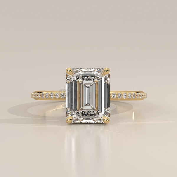 Emerald cut diamond ring with pavé band in yellow gold.
