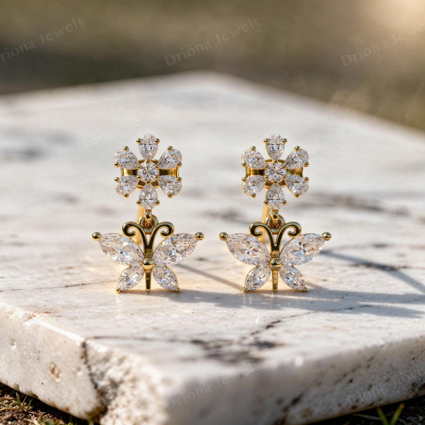 Gold floral drop earrings featuring a marquise diamond butterfly and a sparkling flower cluster.