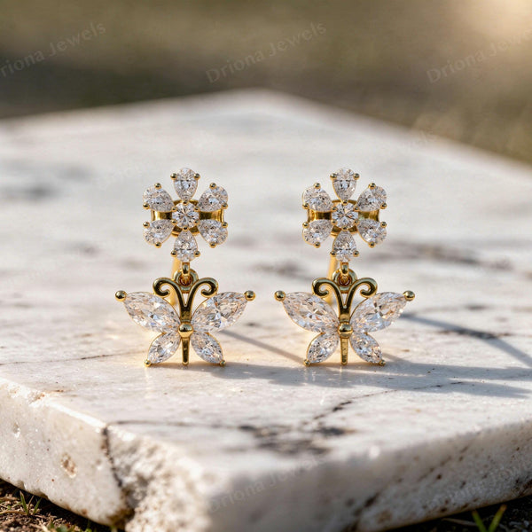 Gold floral drop earrings featuring a marquise diamond butterfly and a sparkling flower cluster.