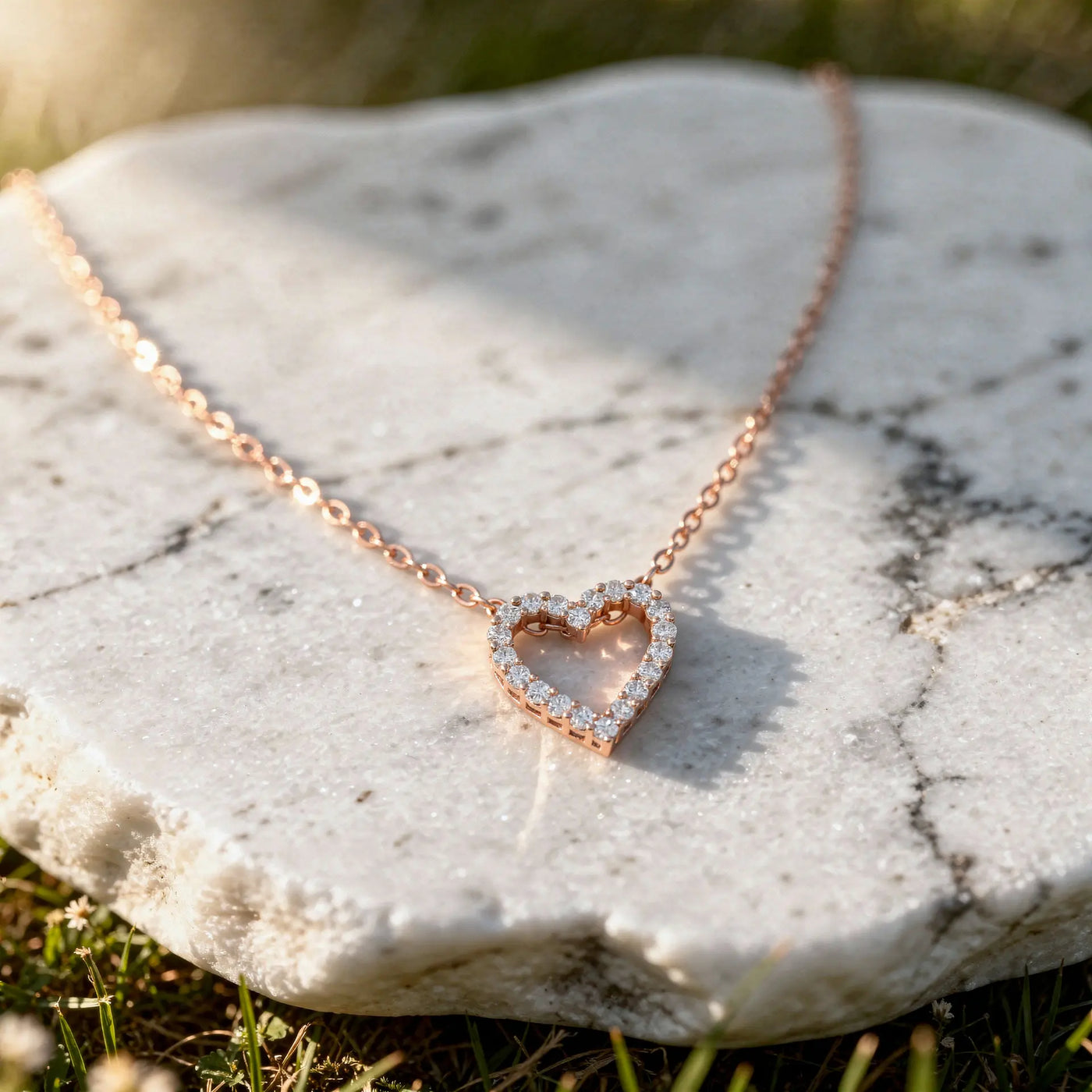 Open heart diamond pendant in 14K gold on a delicate chain, resting on a white marble stone.