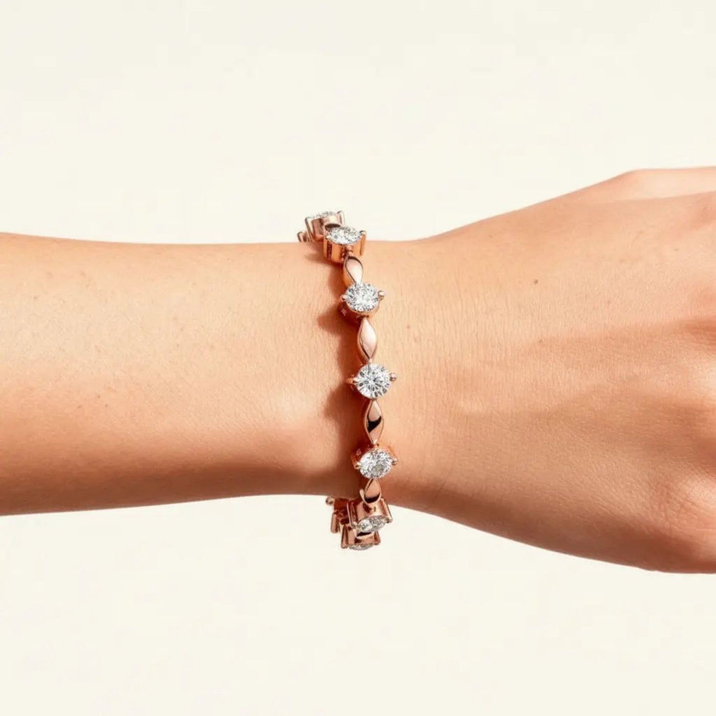 Rose gold bracelet with diamonds on a wrist against a beige background