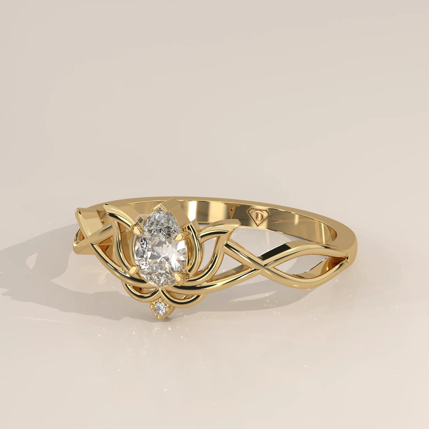 A delicate gold ring featuring a pear-shaped diamond in a lotus design with intertwined band.