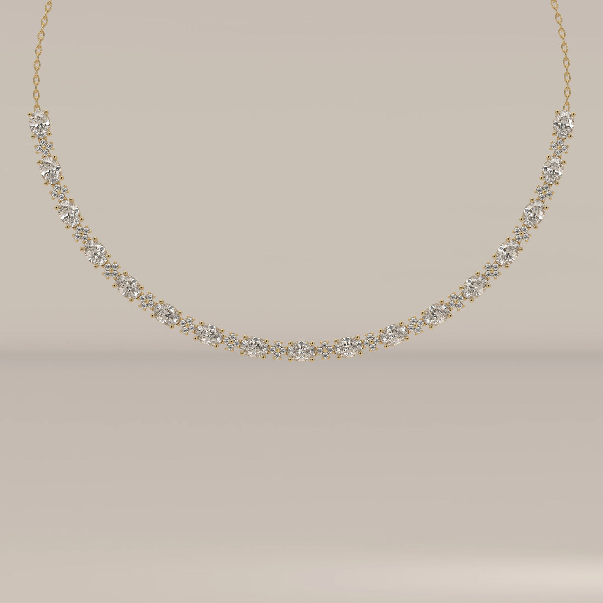 A graduated oval lab grown diamond necklace in yellow gold, shown from the front.