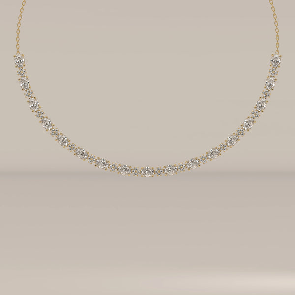 A graduated oval lab grown diamond necklace in yellow gold, shown from the front.