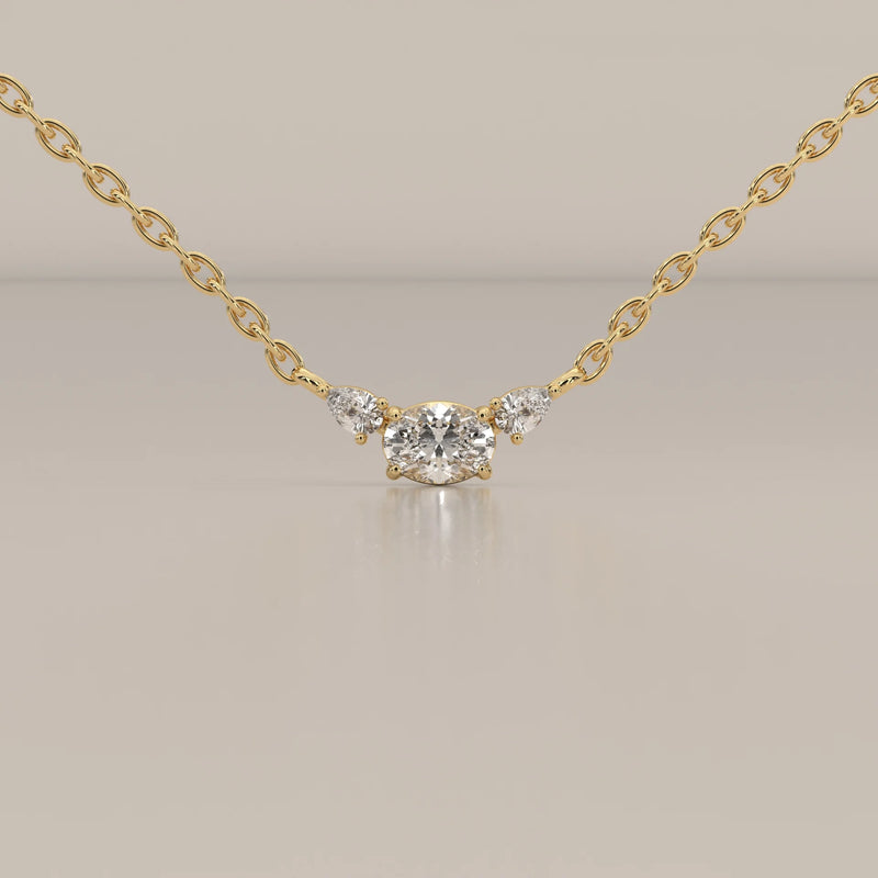 A delicate gold necklace featuring an oval center diamond and two pear-shaped diamonds.