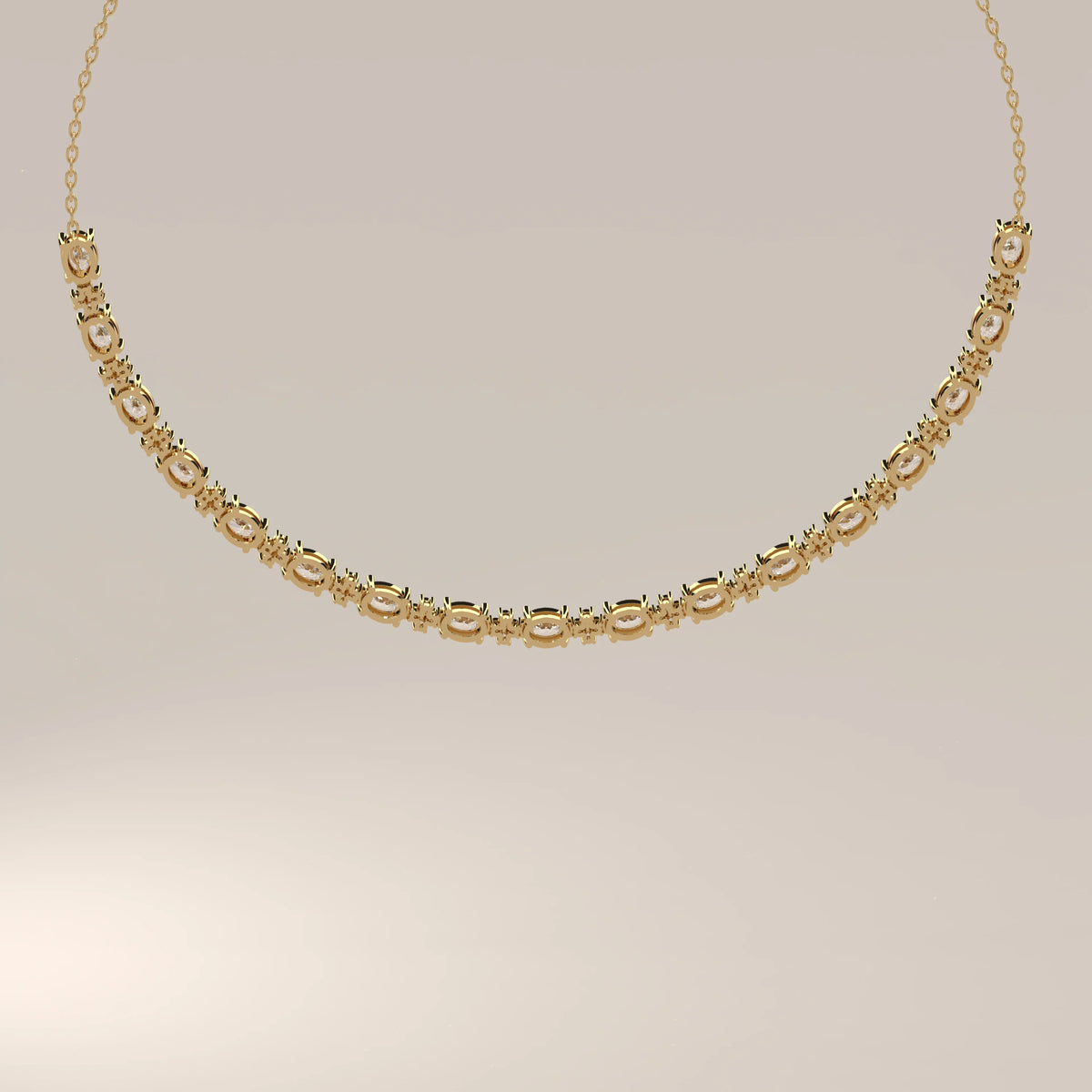 A graduated oval lab grown diamond necklace in yellow gold, studio product photograph.
