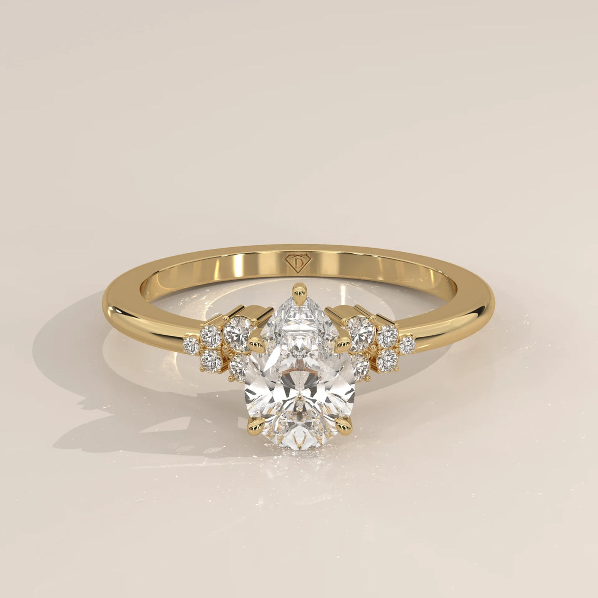 A yellow gold ring with a pear-cut diamond and smaller accent stones.