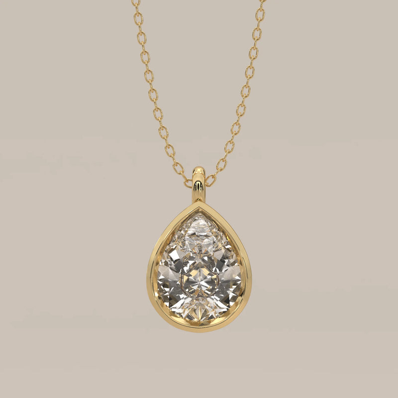 A teardrop pendant with a pear-cut diamond on a yellow gold chain.